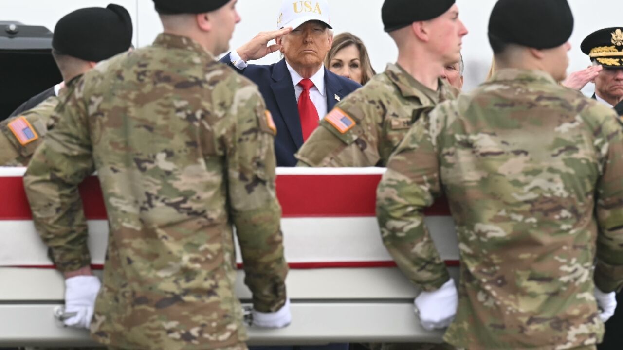 President Donald Trump salutes as members of an Army team carry a case containing the remains of one of six US soldiers killed in an Iranian strike on a US command center in Kuwait