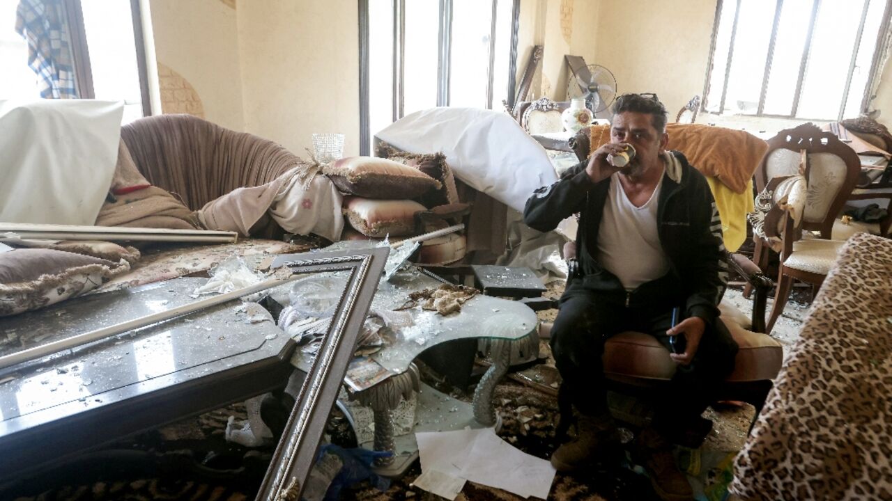 A man drinks tea inside his damaged house after returning to his hometown of Qana in southern Lebanon