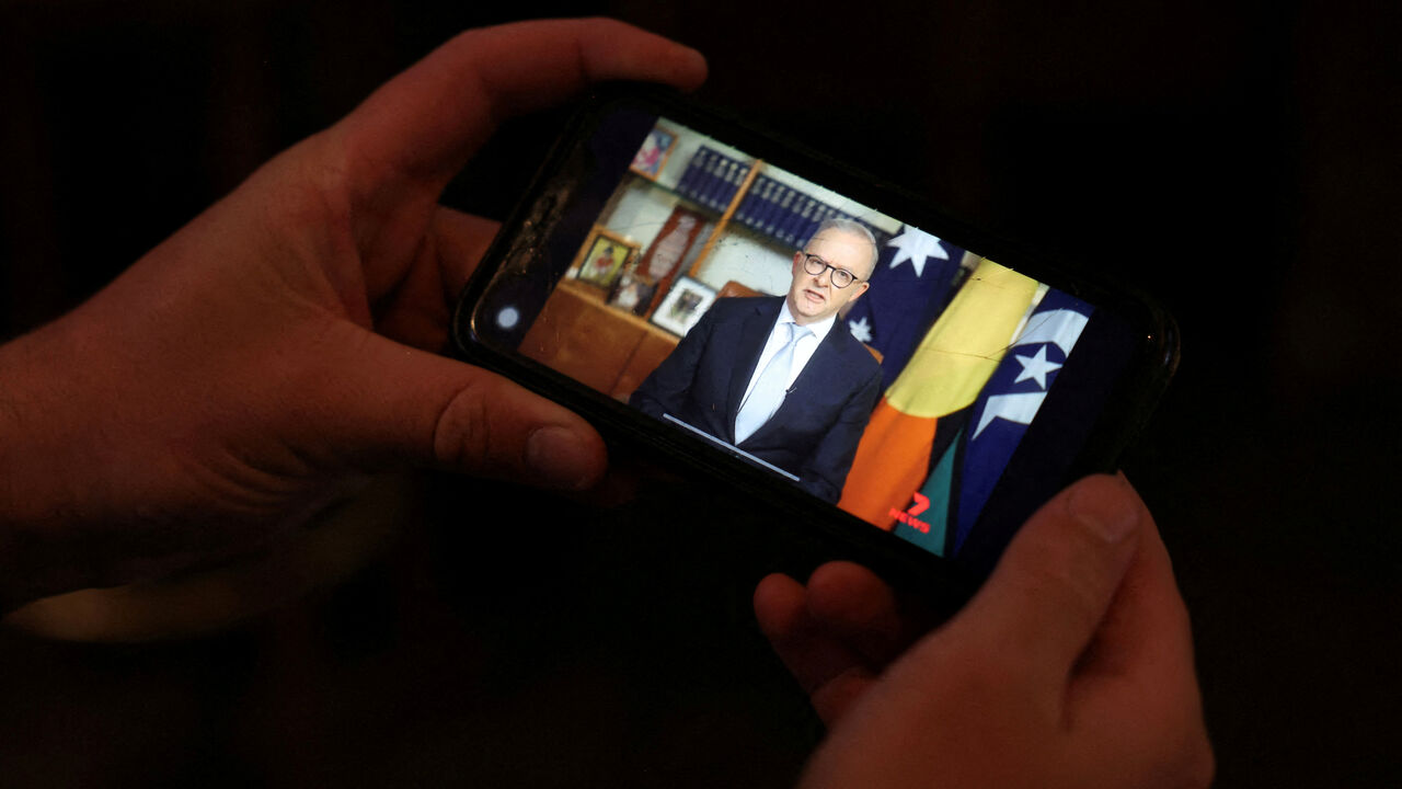 FILE PHOTO: A pub-goer watches Australian Prime Minister Anthony Albanese deliver his address to the nation over the Iran crisis, on his phone at a pub in Sydney, Australia, April 1, 2026. REUTERS/Hollie Adams/File Photo