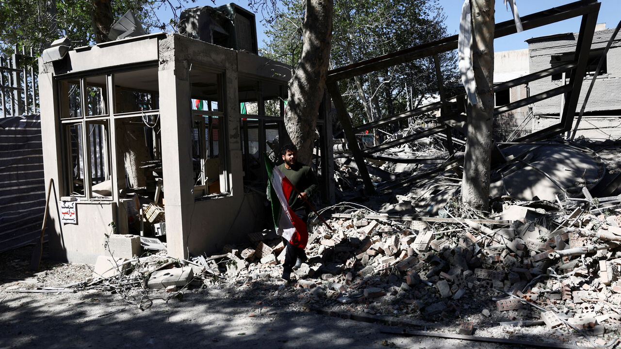 FILE PHOTO: A man carries an Iranian flag as he walks amidst the rubble of a building of the Sharif University of Technology, which was damaged in a strike, amid the U.S.-Israeli conflict with Iran, in Tehran, Iran, April 7, 2026. Majid Asgaripour/WANA (West Asia News Agency) via REUTERS /File Photo