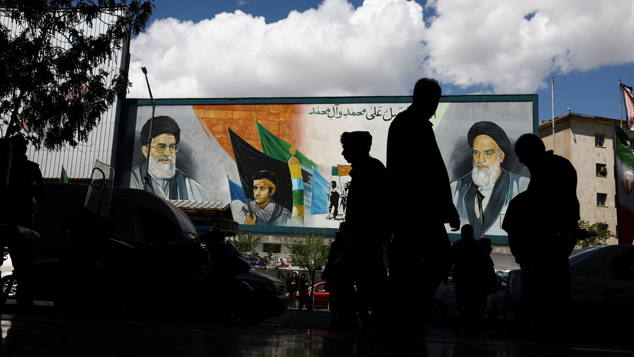People walk next to a mural depicting the late leader of the Islamic Revolution Ayatollah Ruhollah Khomeini and the late Supreme Leader of Iran Ayatollah Ali Khamenei, after U.S. President Donald Trump said that he had agreed to a two-week ceasefire with Iran, in Tehran, Iran, April 8, 2026. Majid Asgaripour/WANA (West Asia News Agency) via REUTERS