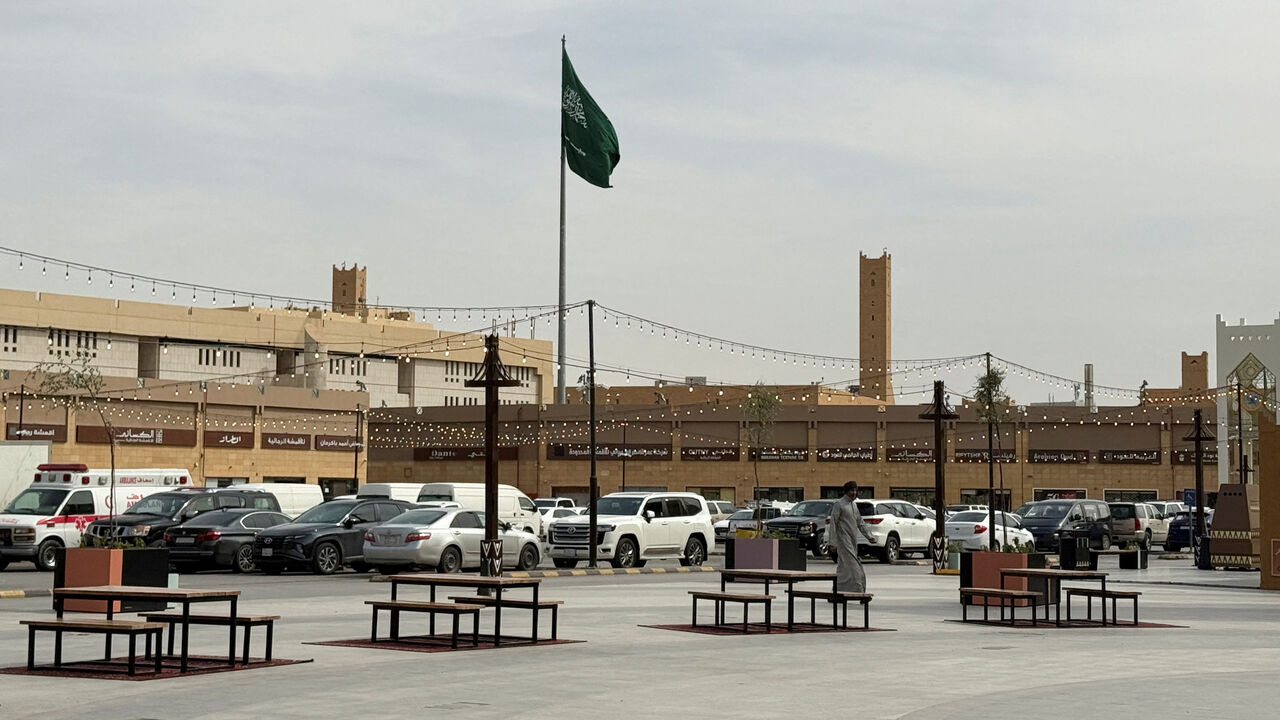 A man walks as a Saudi flag flutters in the background at Al Qaisareyah Market, amid the U.S.-Israeli conflict with Iran, in Riyadh, Saudi Arabia, March 4, 2026. Picture taken with a mobile phone. REUTERS/Ibraheem Abu Mustafa