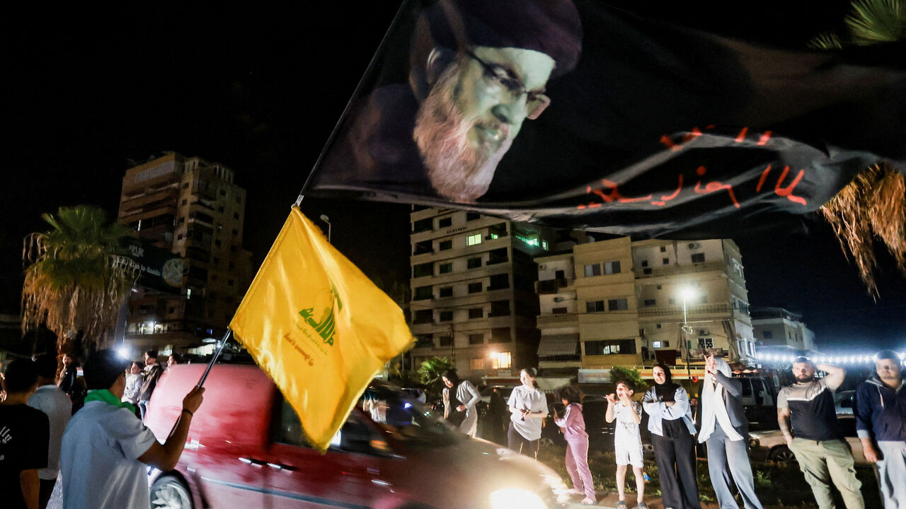 A man holds a large flag with an image depicting former Hezbollah leader Hassan Nasrallah, as displaced people return to their homes after a 10-day ceasefire between Lebanon and Israel went into effect, in Sidon, Lebanon, April 17, 2026. REUTERS/Aziz Taher