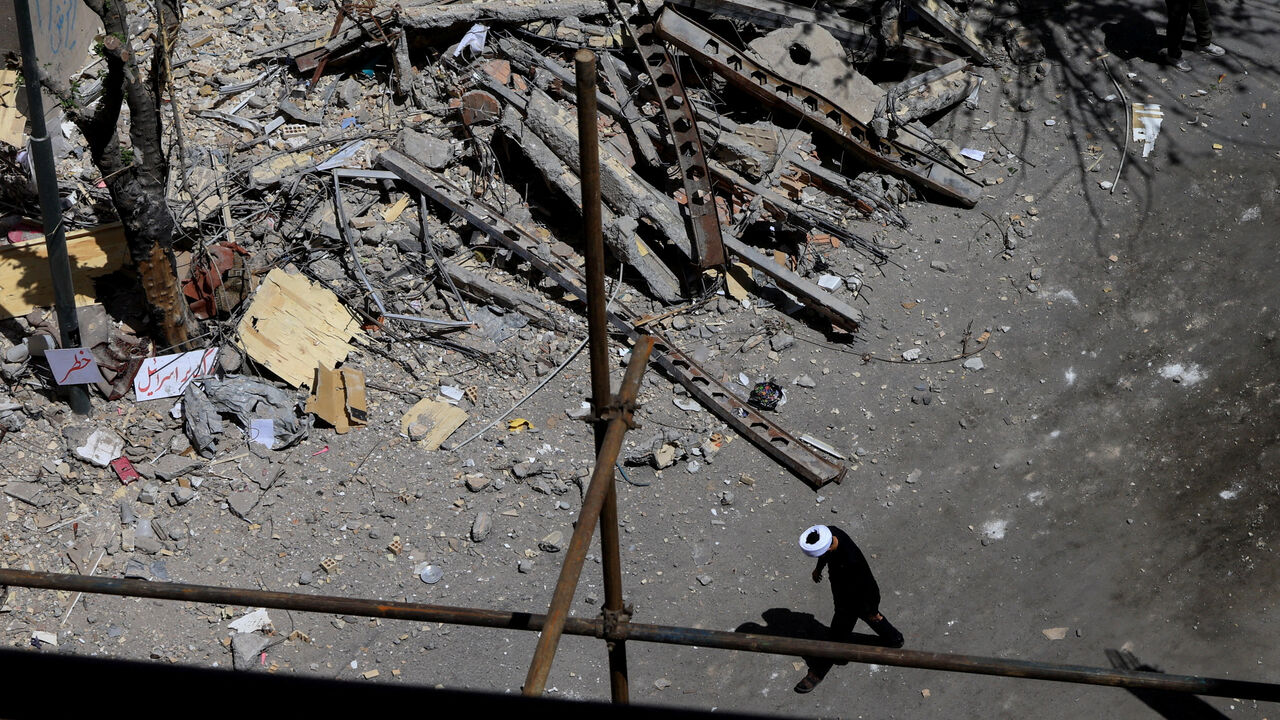 A cleric walks near a residential building damaged by a strike on March 4, in Tehran, Iran, April 14, 2026. REUTERS/Thaier Al Sudani