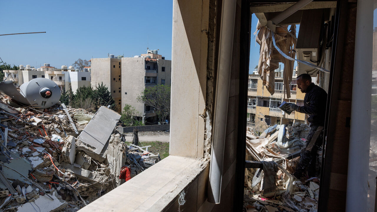 A man checks a book that was found among rubble as he cleans an apartment in a building damaged by an Israeli strike, amid a temporary ceasefire between Lebanon and Israel, in Tyre, April 23, 2026. REUTERS/Zohra Bensemra