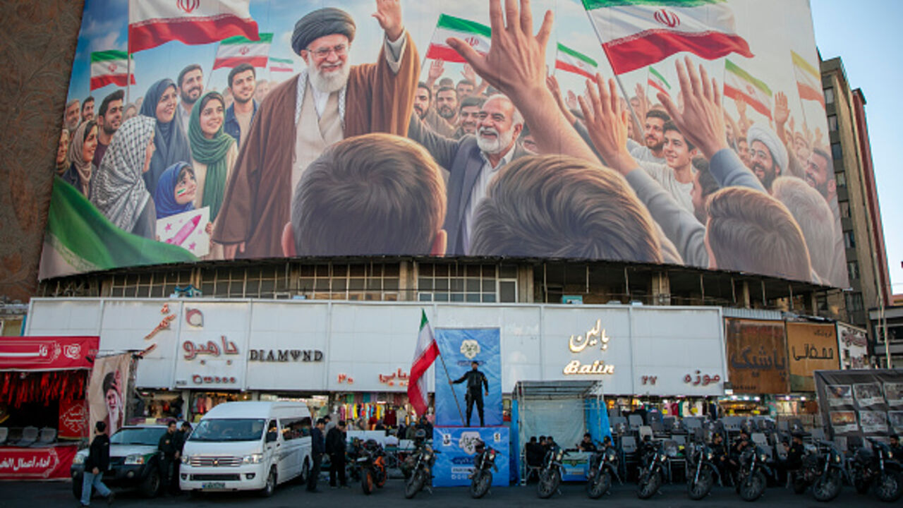 TEHRAN, IRAN - APRIL 23: A police officer stands holding a flag in Valiasr Square beneath a mural of the late Ayatollah Ali Khamenei on April 23, 2026 in Tehran, Iran. Earlier this week, U.S. President Donald Trump announced an extension of the current ceasefire between his country and Iran, despite Iran declining to attend the latest proposed round of peace talks in Islamabad. The focus of the war has shifted largely to the Strait of Hormuz, where both sides are trying to assert control over the critical m