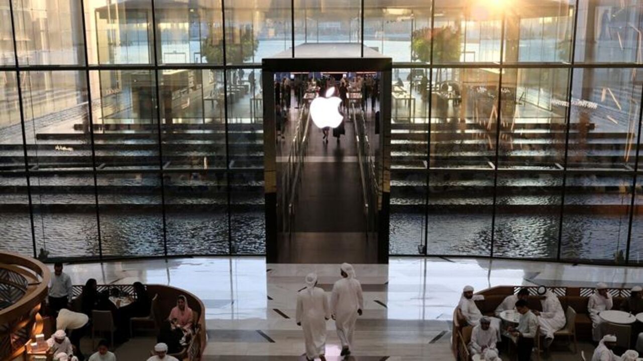 People sit in a cafe outside the Apple Store in Dubai on May 8, 2025. — GIUSEPPE CACACE/AFP via Getty Images