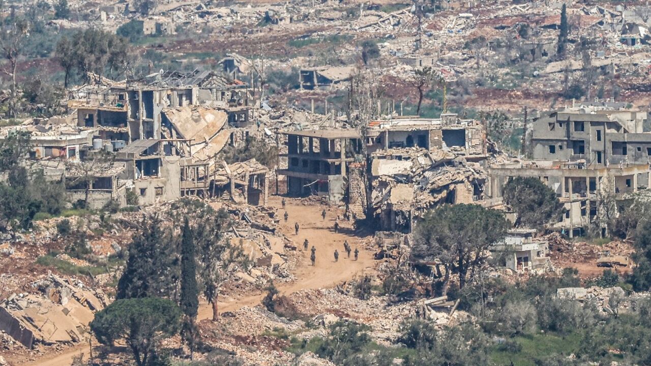 Israeli soldiers walking along the road between destroyed houses in southern Lebanon 