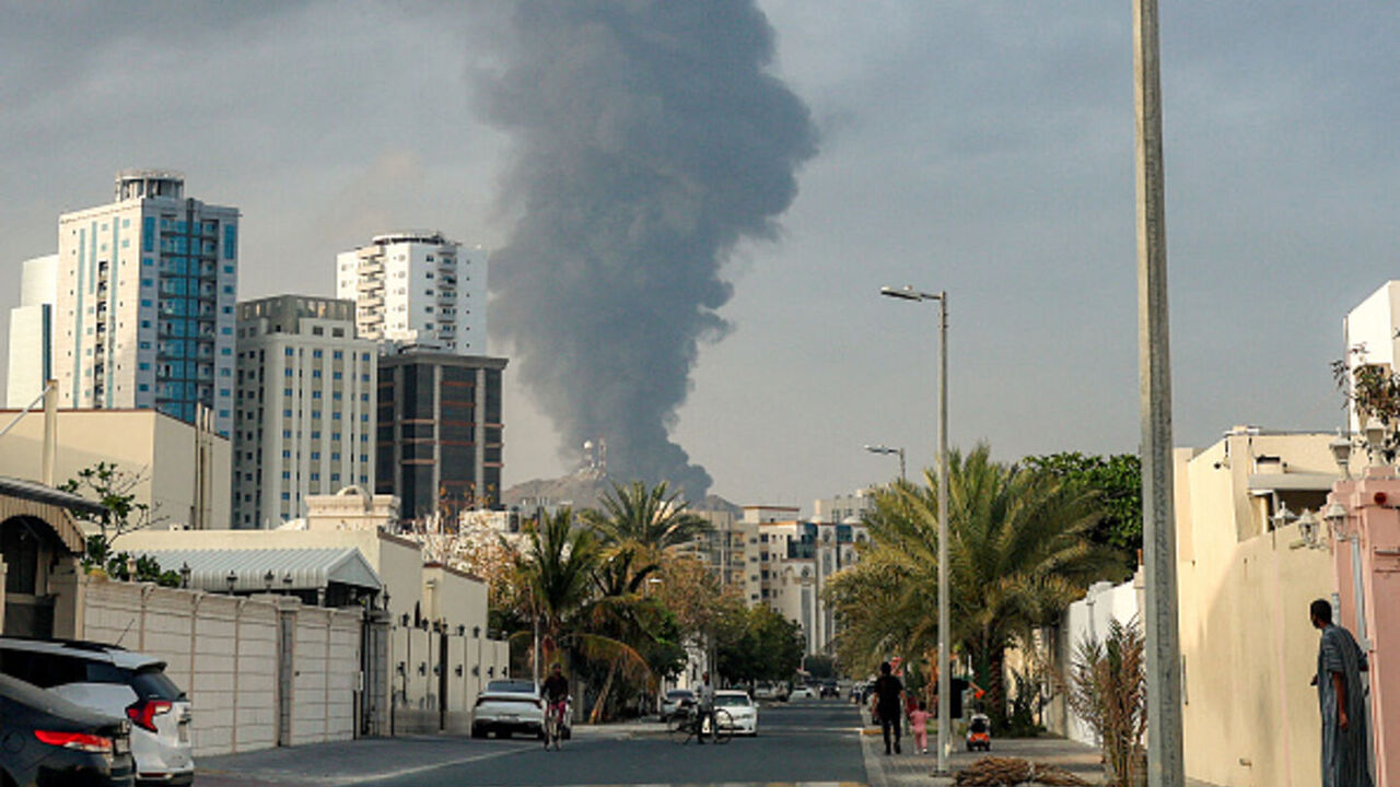 People watch from a street as a tall smoke plume billows following an explosion in the United Arab Emirates' Fujairah industrial zone on March 3, 2026. — Fadel SENNA / AFP via Getty Images
