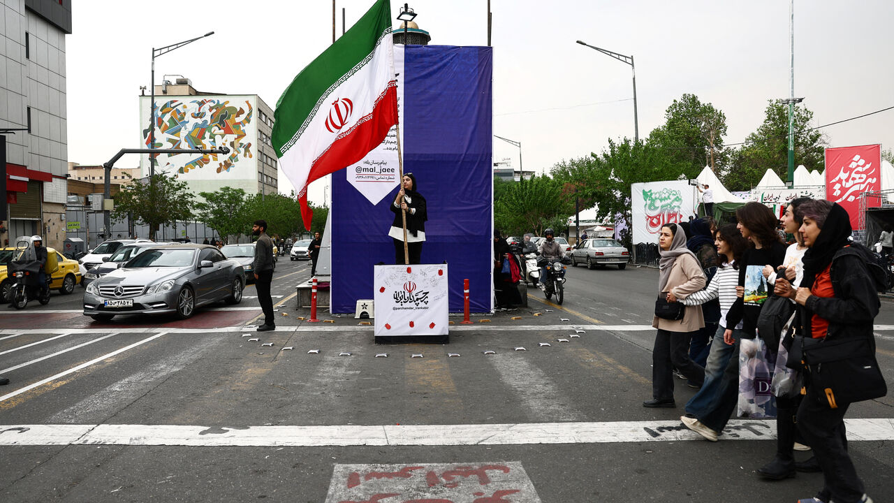 A woman holds an Iranian flag on a street, amid a ceasefire between U.S. and Iran, in Tehran, Iran, April 20, 2026. Majid Asgaripour/WANA (West Asia News Agency) via REUTERS ATTENTION EDITORS - THIS PICTURE WAS PROVIDED BY A THIRD PARTY