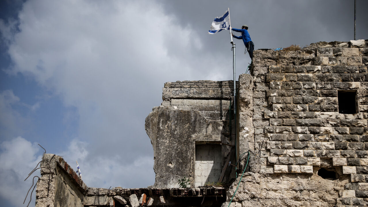 An Israeli settler places an Israeli flag, on the day of the re-establishment of the settlement of Sa-Nur, which was evacuated as part of Israel’s 2005 disengagement, in Sa-Nur in the Israeli-occupied West Bank, April 19, 2026. REUTERS/Shir Torem