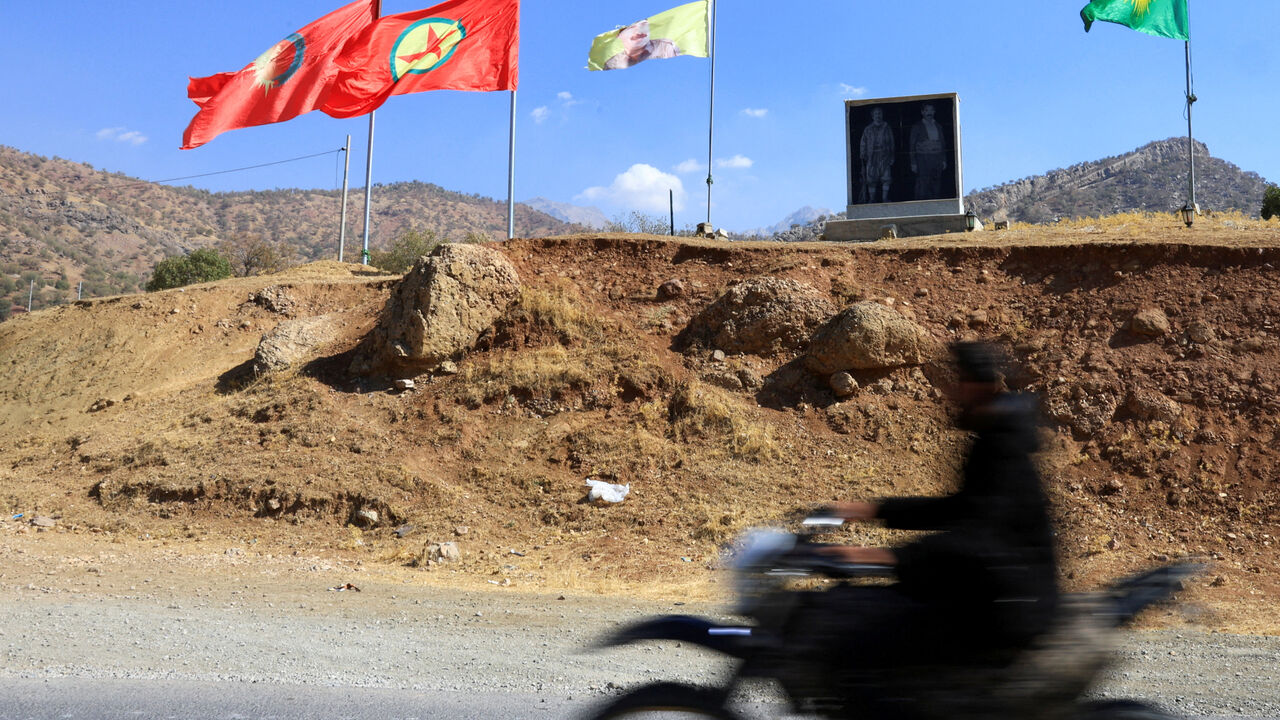 FILE PHOTO: A fighter with the Kurdistan Workers' Party (PKK) rides a motorcycle past flags in the Qandil mountains, Iraq, October 26, 2025. REUTERS/Thaier Al-Sudani/File Photo