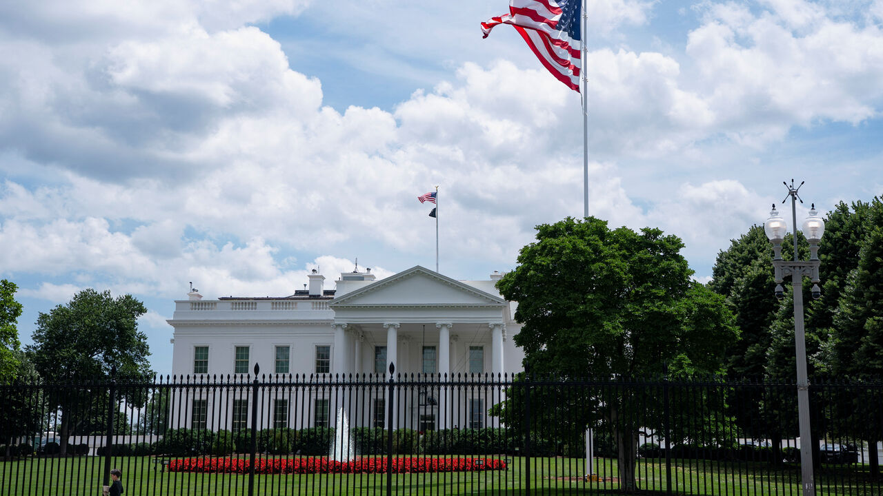 A visitor walks past the White House and a new flag pole installed on the North Lawn in Washington, D.C., U.S., June 19, 2025. REUTERS/Nathan Howard
