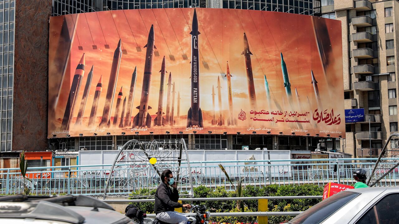 Traffic passes a billboard depicting Iranian ballistic missiles in service, with text in Arabic reading "the honest [person's] promise" and in Persian "Israel is weaker than a spider's web," Valiasr Square, Tehran, April 15, 2024. ATTA KENARE/AFP via Getty Images.