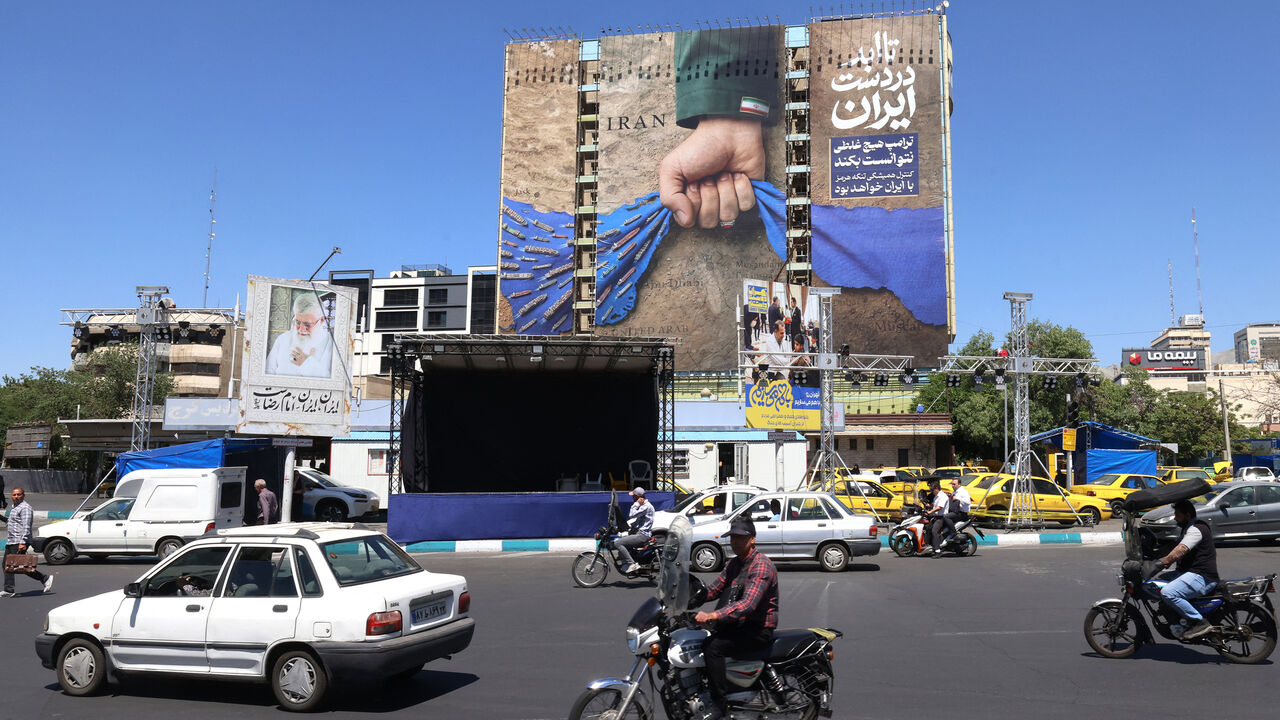 Vehicles drive past a billboard on the facade of a building depicting the Strait of Hormuz with a caption in Persian reading, "Forever in Iran's Hand," at Vanak Square, Tehran, Iran, May 25, 2026.