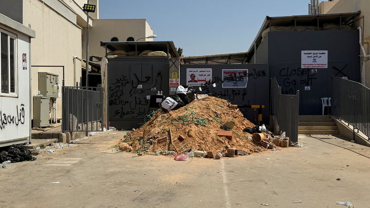 FILE PHOTO: A poster with a crossed-out picture of Tripoli's Chief of Mission at UNHCR, Sakhr Karmen, and spray-painted walls calling for demanding the organisation leave the country and calling for an end to migrant settlement and the deportation of migrants and refugees, outside the headquarters in Tripoli, Libya, June 4, 2026. Picture taken with a mobile phone. REUTERS/Ayman al-Sahili/File Photo
