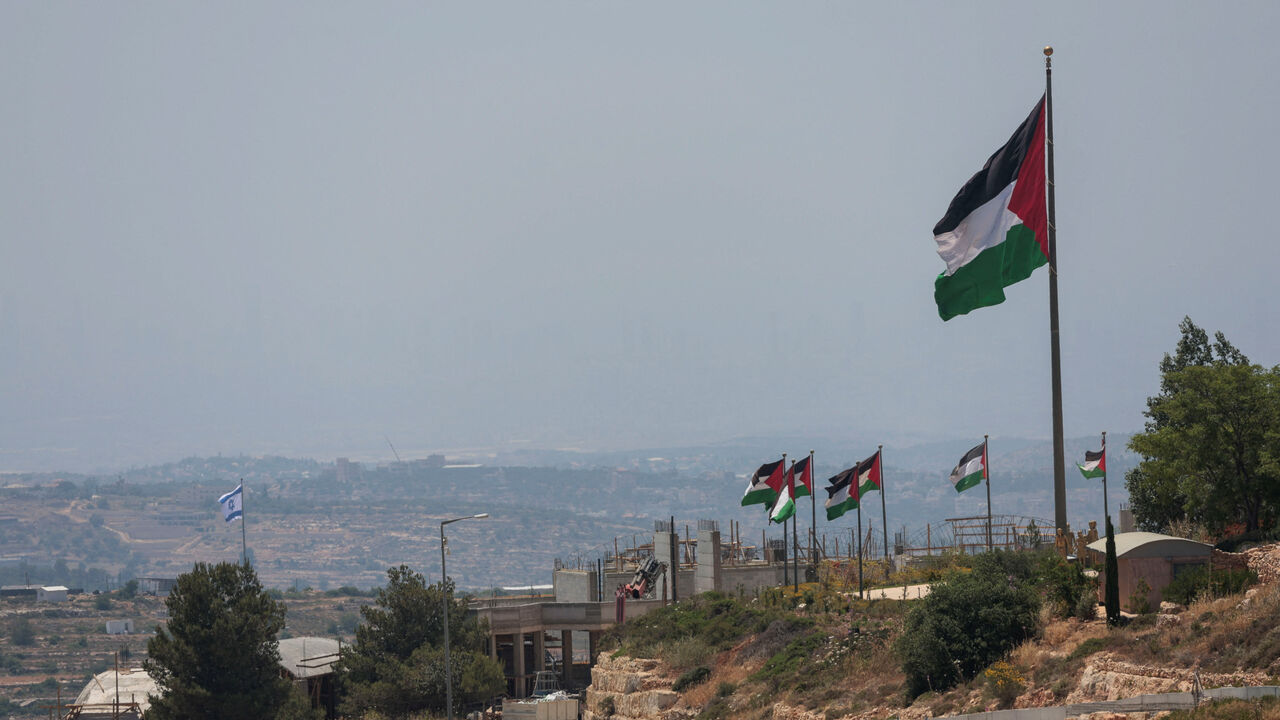 An Israeli flag flutters at a new Israeli settlement, behind Palestinians flags near Ramallah, in the Israeli-occupied West Bank, Jun 1, 2026. REUTERS/Mohammed Torokman