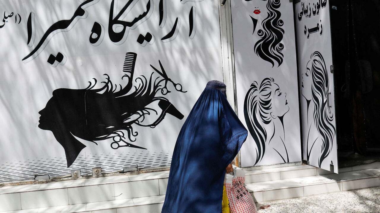 FILE PHOTO: An Afghan woman walks past a beauty salon in Kabul, Afghanistan, July 6, 2023. REUTERS/Ali Khara/File Photo
