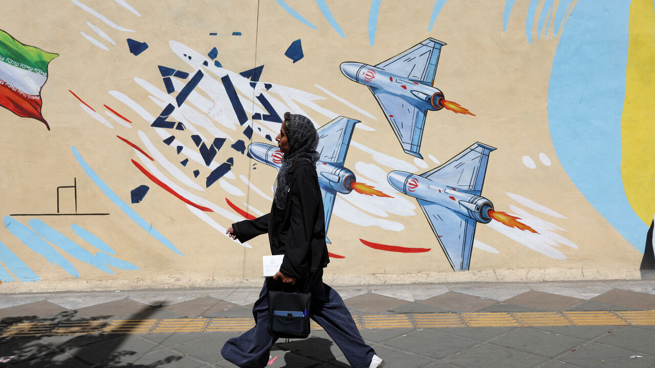 An Iranian woman walks past an anti-Israeli mural, after U.S. and Iranian officials said they had reached a deal to end their war and reopen the Strait of Hormuz, in Tehran, Iran, June 15, 2026. Majid Asgaripour/WANA (West Asia News Agency) via REUTERS