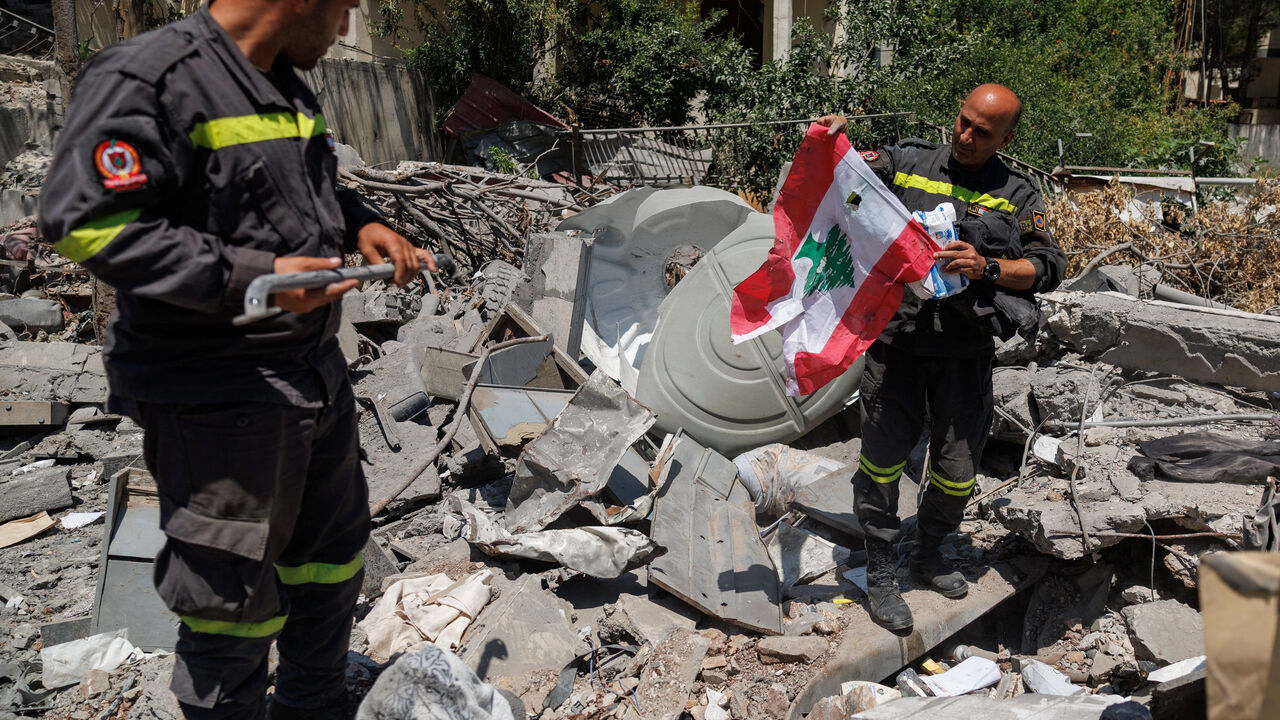 A member of the government-run Lebanese Civil Defense, the country's primary firefighting, first aid, and rescue force, holds a Lebanese flag salvaged from the rubble while inspecting their headquarters in Nabatieh, Lebanon, June 17, 2026, following the deal between the United States and Iran. The headquarters was destroyed in an Israeli airstrike in May. REUTERS/Zohra Bensemra