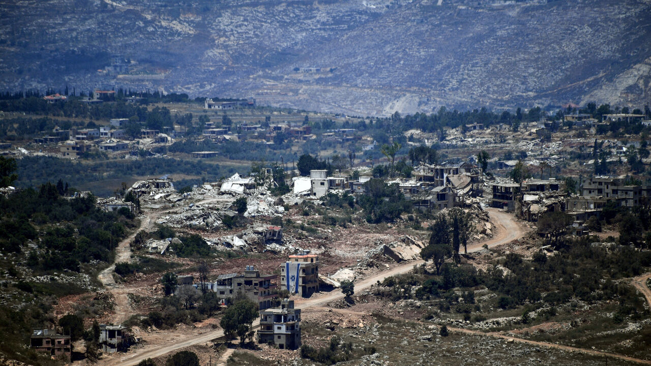 An Israeli flag hangs from a damaged building in a village inside south Lebanon close to the border as seen from northern Israel, June 18, 2026. REUTERS/Gil Eliyahu