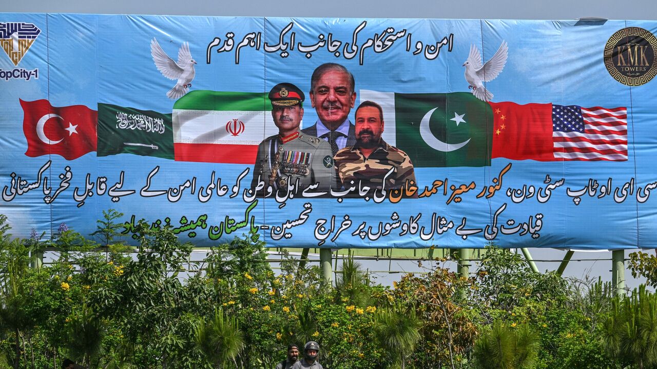 Motorcyclists ride past a billboard featuring Pakistan's Prime Minister Shehbaz Sharif (C) and Army Chief and Field Marshal Syed Asim Munir (L) in Islamabad on April 20, 2026, ahead of anticipated US-Iran peace talks. 