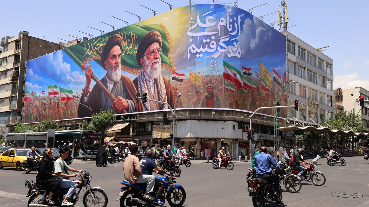 People ride motorcycles past a large billboard showing portraits of Iran's late supreme leader, Ayatollah Ruhollah Khomeini (L), and slain supreme leader Ayatollah Ali Khamenei (R) in central Tehran on June 8, 2026. 