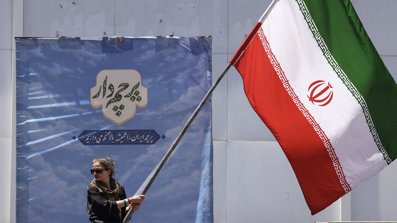An Iranian woman waves a national flag at Valiasr Square in Tehran on June 15, 2026. 