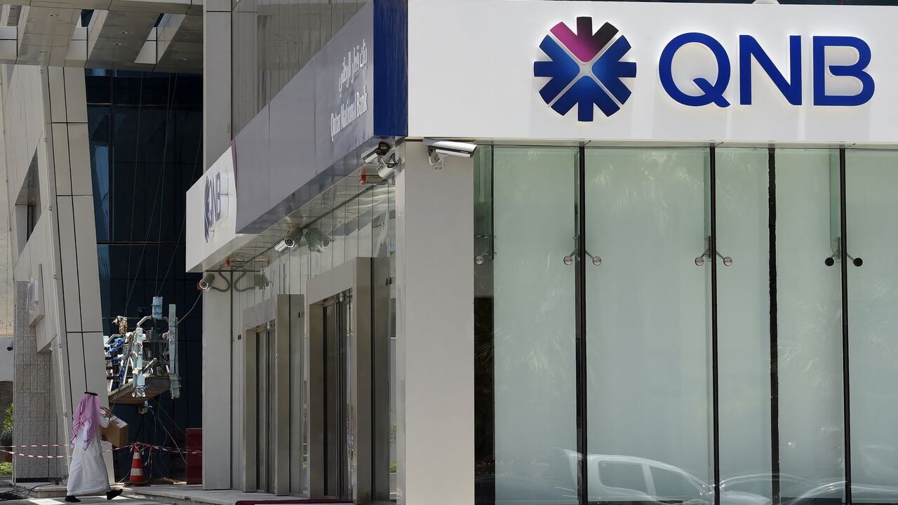 A picture taken on June 5, 2017, shows a man walking past the Qatar National Bank branch in the Saudi capital Riyadh. 