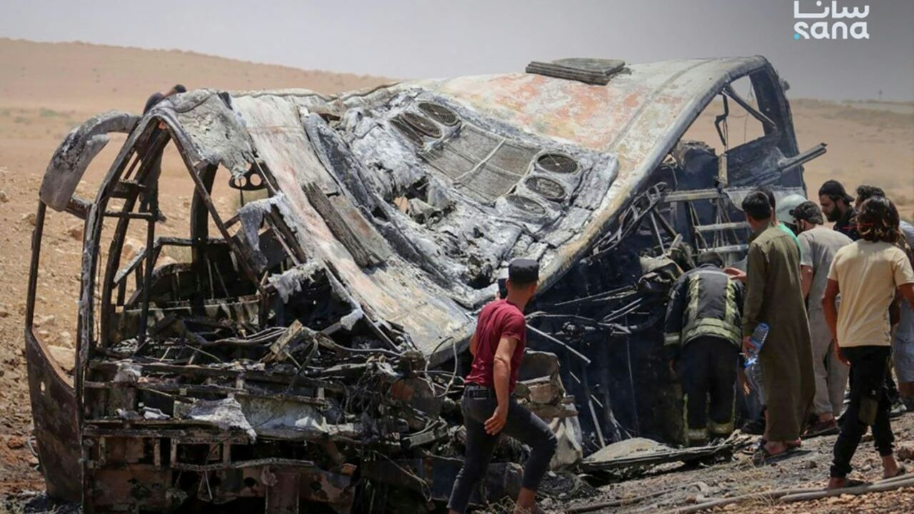This handout picture taken and released by the official Syrian Arab News Agency (SANA) on July 25, 2026 shows people and first responders inspecting the damage at the scene of the collision of two passenger buses on the Damascus-Deir Ezzor road