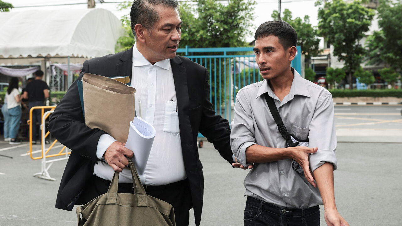 Noppadon Wongsuvan, 33, a Thai crew member of the cargo ship Mayuree Naree that was struck on March 11, killing three crew members, while sailing through the Strait of Hormuz, and his lawyer, Kunpat Singhathong, arrive at the Central Labour Court to file a lawsuit accusing Thailand-based company Precious Shipping of ordering the vessel to sail through the waterway despite military tensions between the U.S. and Iran, in Bangkok, Thailand, July 10, 2026. REUTERS/Chalinee Thirasupa