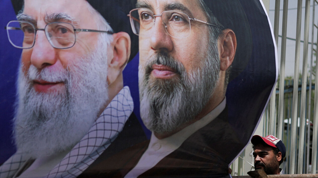 A man mounts a banner depicting Iran's late Supreme Leader Ayatollah Ali Khamenei and Iran's Supreme Leader Ayatollah Mojtaba Khamenei, onto a fence during preparations for a farewell ceremony for Iran's late Supreme Leader Ayatollah Ali Khamenei who was killed on February 28 in Israeli and U.S. airstrikes, otside the Imam Khomeini Grand Mosalla, in Tehran, Iran July 2, 2026. REUTERS/Mohammed Salem