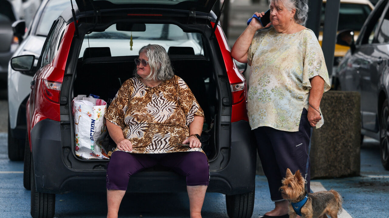 A woman carries a dog at the Bordeaux-Lac Exhibition Centre, which has been turned into a shelter for people displaced by a wildfire burning nearby amid worsening drought conditions following a heatwave and water shortages across much of France, in Bordeaux, Gironde, France, July 26, 2026. REUTERS/Florion Goga
