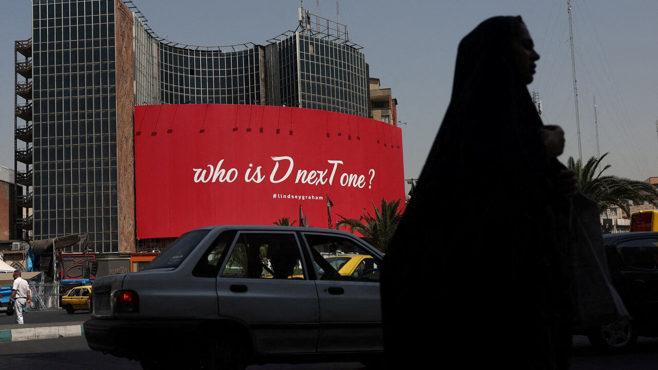 A woman walks near a billboard with a slogan referring to U.S. President Donald Trump and a hashtag referring to late U.S. Senator Lindsay Graham, in Tehran, Iran, July 27, 2026. Majid Asgaripour/WANA (West Asia News Agency) via REUTERS