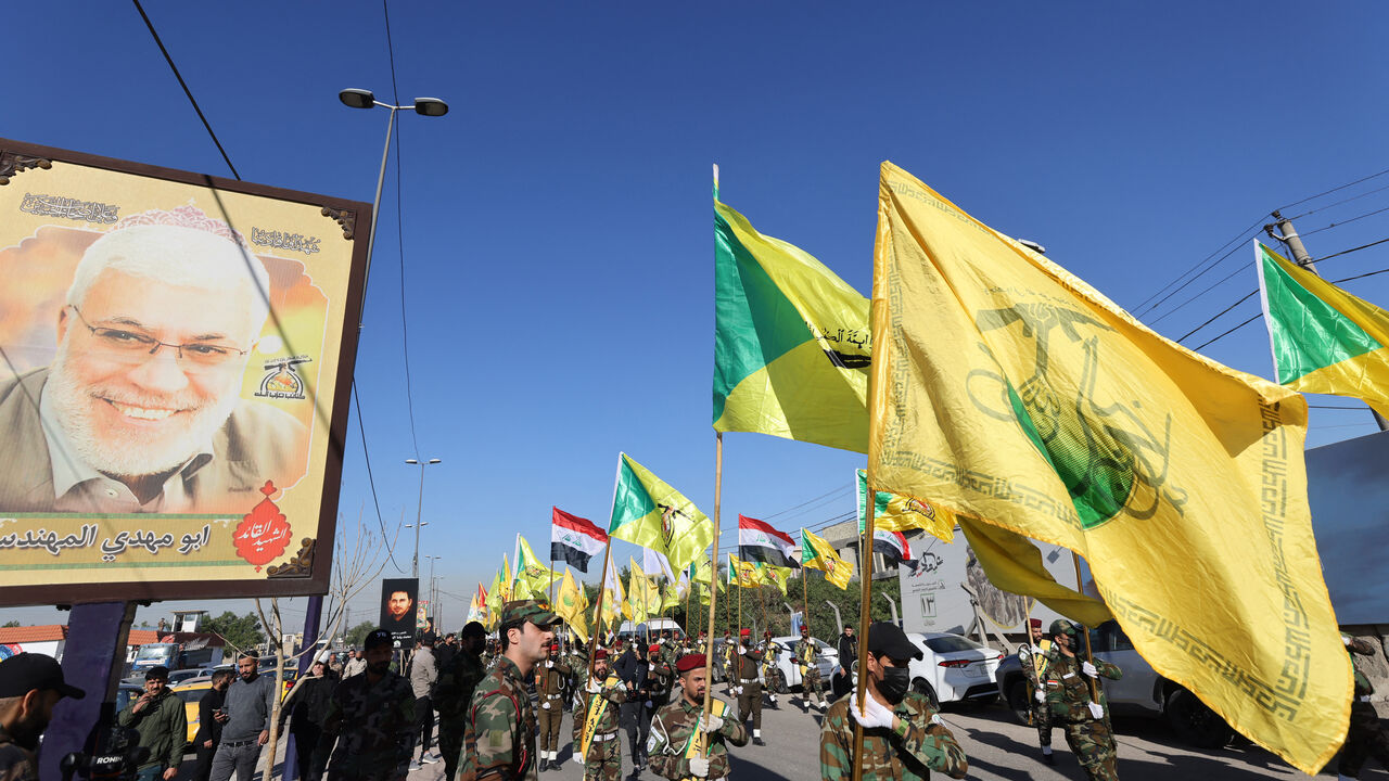 Fighters lift flags of Iraq and paramilitary groups, including al-Nujaba and Kataib Hezbollah, during a funeral in Baghdad for five militants killed a day earlier in a US strike in northern Iraq, on Dec. 4, 2023. 