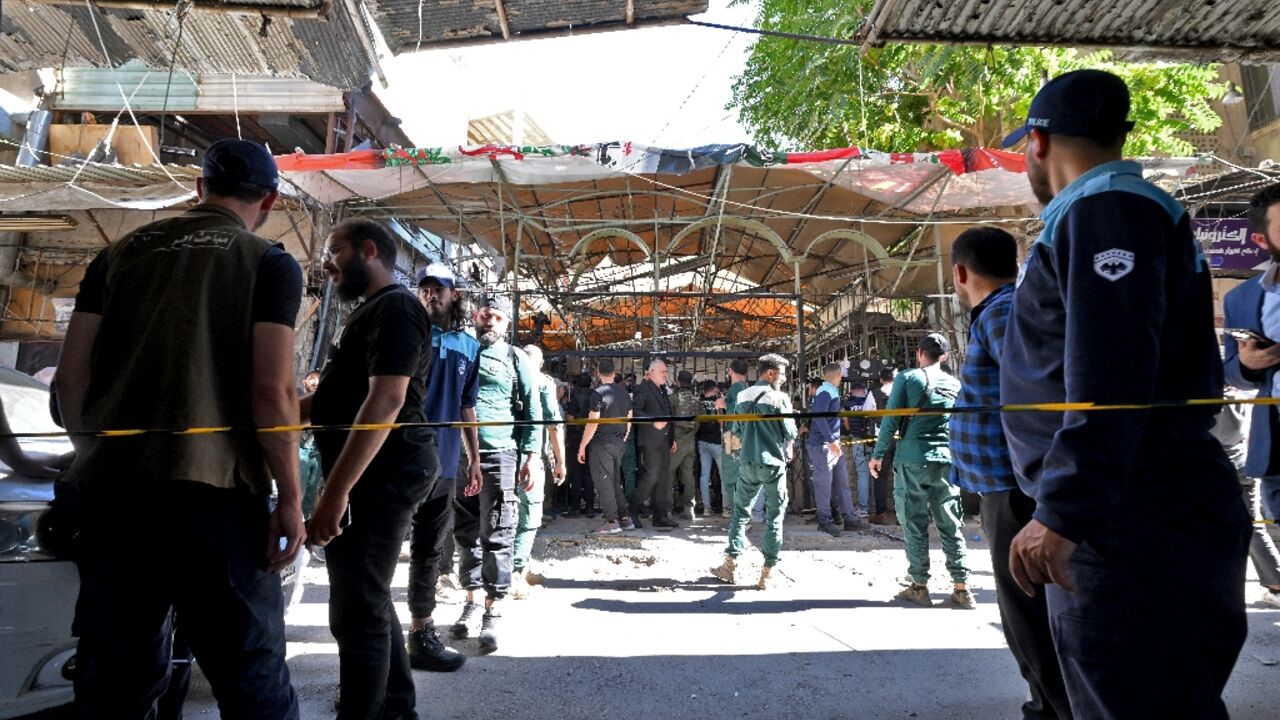 Syrian security forces and bystanders gather at the site of an explosion at a cafe in Damascus on Thursday