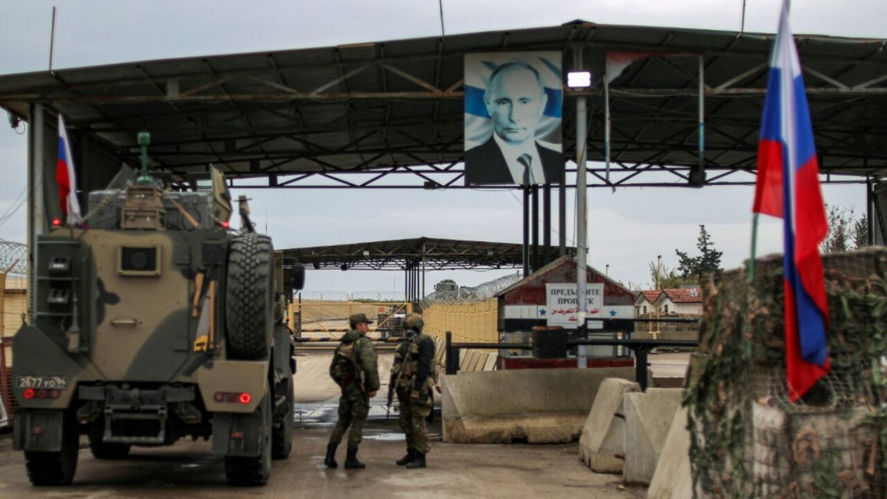 A portrait of Russia's President Vladimir Putin hangs above the military base of Hmeimim in Latakia province in western Syria in 2024