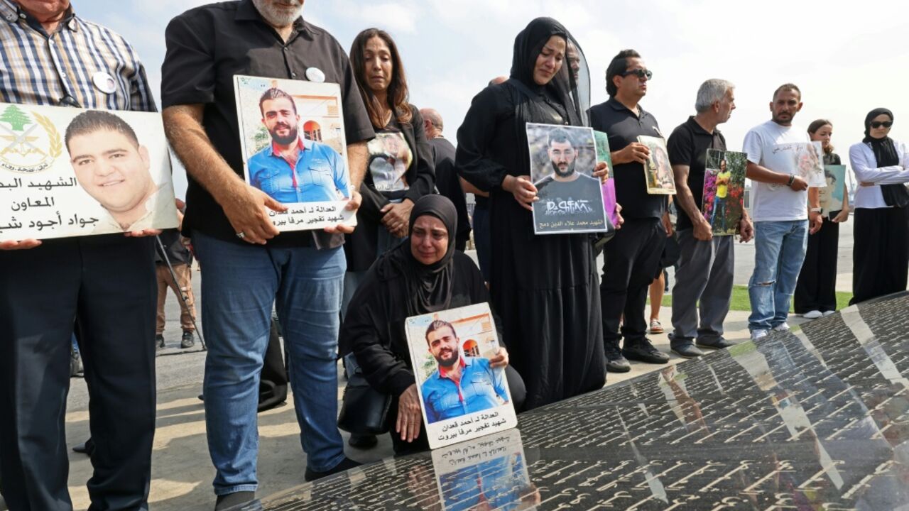 Family members carry the portraits of the victims of 2020 Beirut port blast as they gather around the marble memorial engraved with the names of the victims near the blast's ground zero