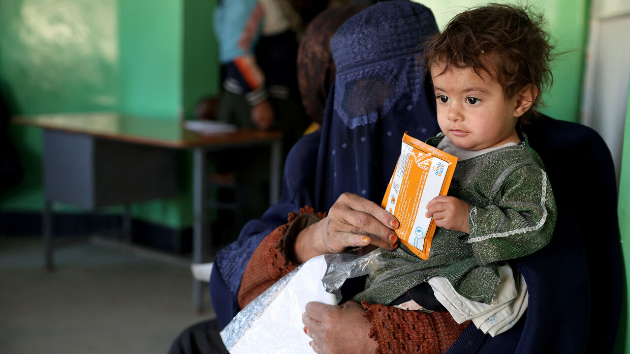 Halima, 40, holds her child with a sachet of Plumpy’Nut, while sitting on a bench at the WFP-supported Qasaba Clinic after an increase in malnutrition cases following the return of deported Afghans, in Kabul, Afghanistan, January 7, 2026. REUTERS/Sayed Hassib