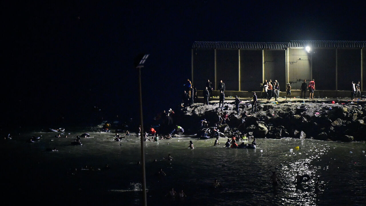 Migrants from Morocco cross into Ceuta by sea as other gather near the border fence between the Spanish enclave of Ceuta and Morocco, as seen from Ceuta, Spain, July 30, 2026. REUTERS/Fabian Bimmer