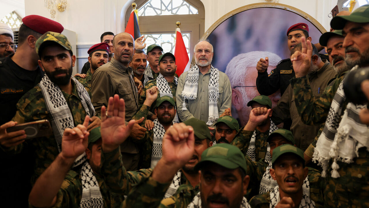 Iranian Parliament Speaker Mohammad Baqer Qalibaf stands with members of Iraq's Popular Mobilization Forces at the grave of Iraqi paramilitary commander Abu Mahdi al-Muhandis, who was killed alongside Iranian military commander Qassem Soleimani in a U.S. drone strike near Baghdad International Airport in January 2020, in Najaf, Iraq, August 21, 2026. REUTERS/Ahmed Saad