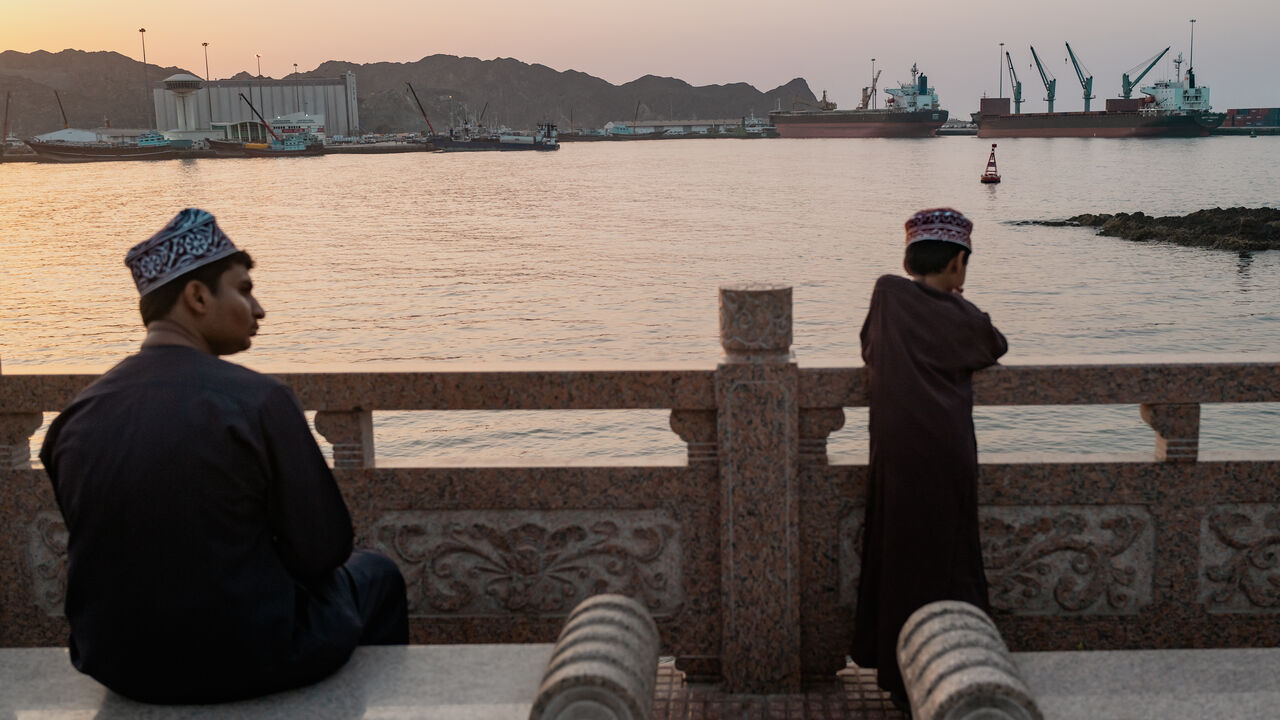 Two brothers watch oil tankers, general cargo ships, bulk carriers, and fishing boats anchored in the waters off Muscat near the Strait of Hormuz on June 18, 2026 in Muscat, Oman.