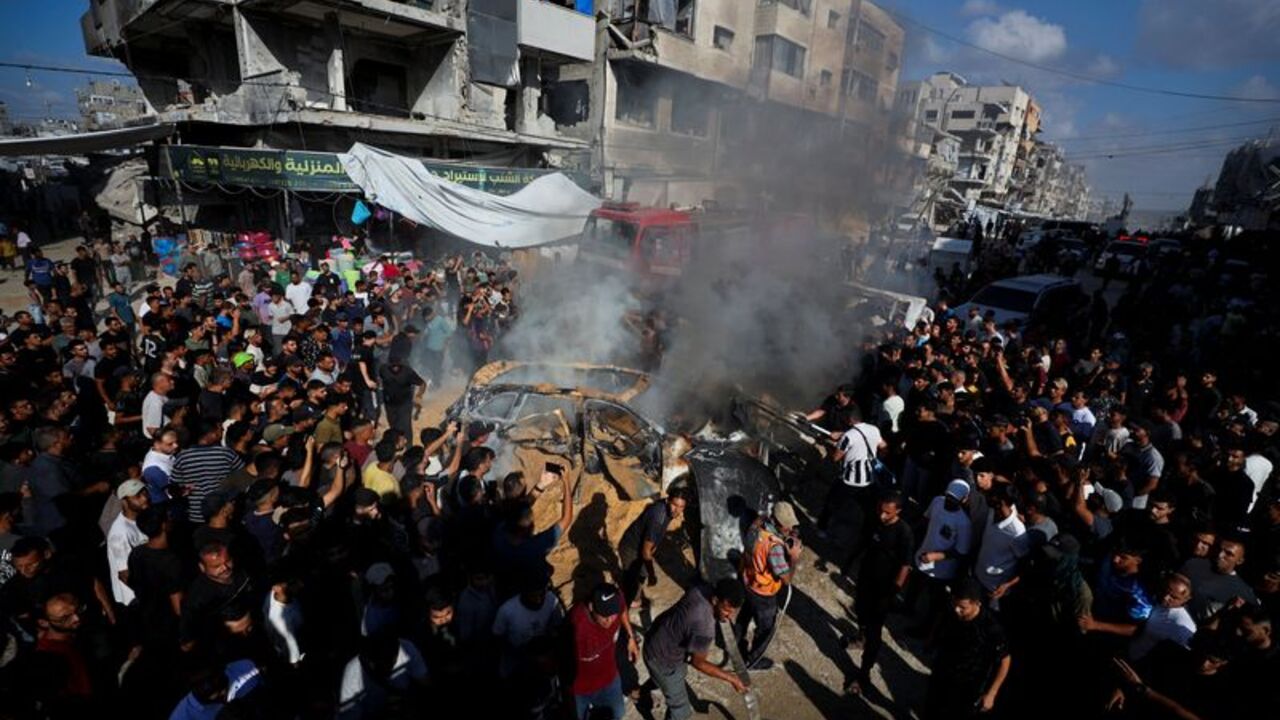 Palestinians attempt to extinguish a fire following an Israeli airstrike that hit a vehicle in Gaza City