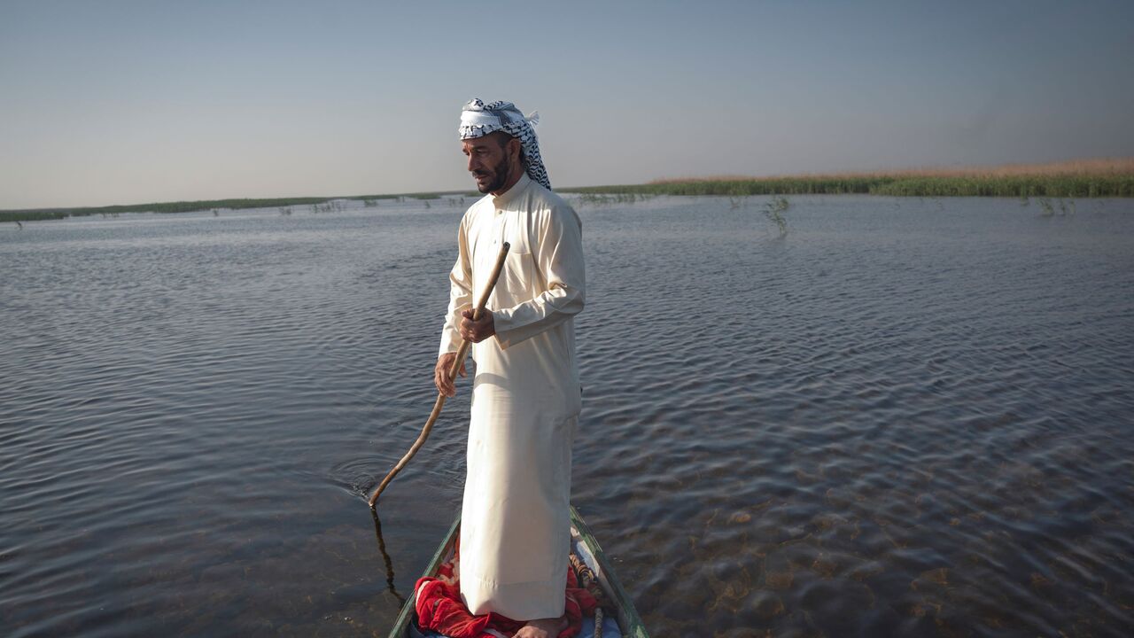 A man uses a pole to navigate a boat