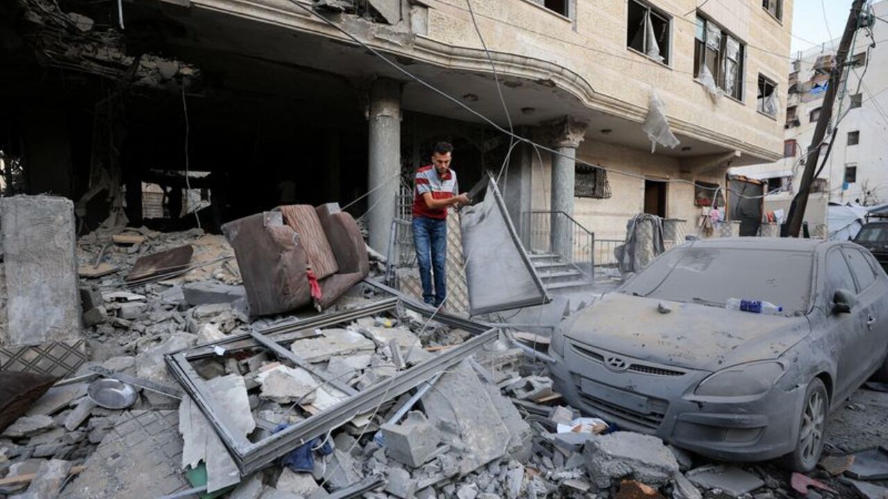 Palestinians inspect the site of an Israeli strike on an apartment building in Gaza City