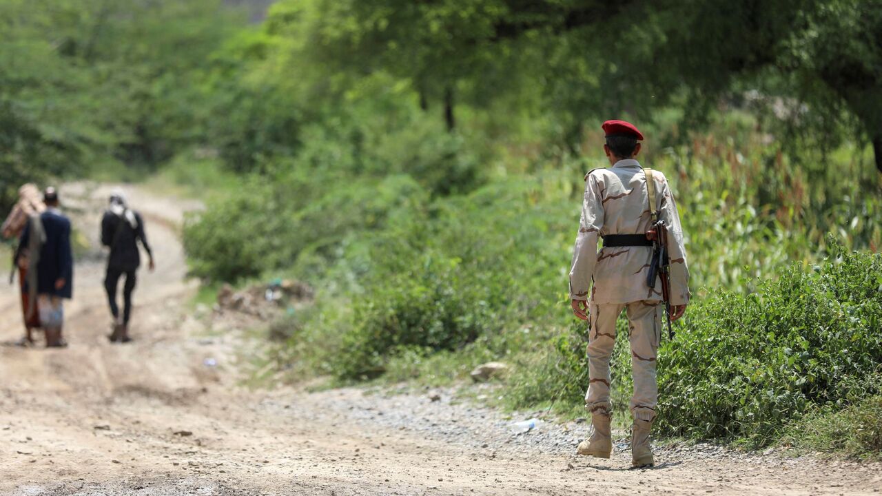 Saudi-backed Yemeni government forces walk along a dirt road