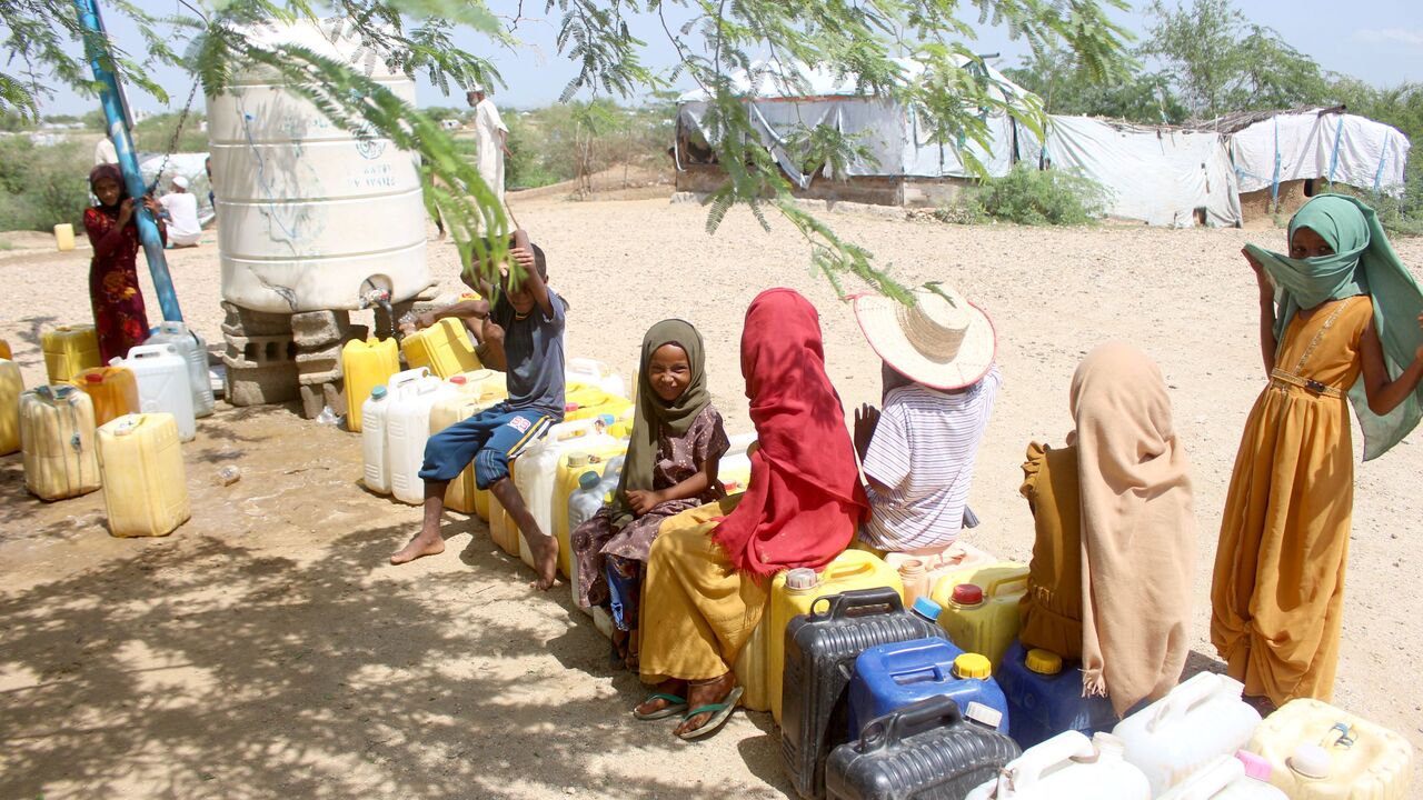 Internally displaced Yemenis queue at a water tank dispenser