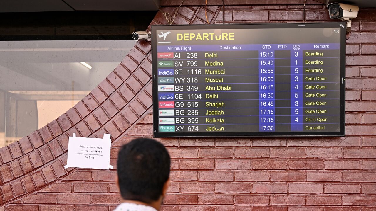 A man looks at a screen displaying the flight schedule at the Hazrat Shahjalal International Airport in Dhaka, on Oct. 12, 2026, as Saudi Arabia-bound flights remain canceled a day after a Houthi strike at Riyadh's international airport.