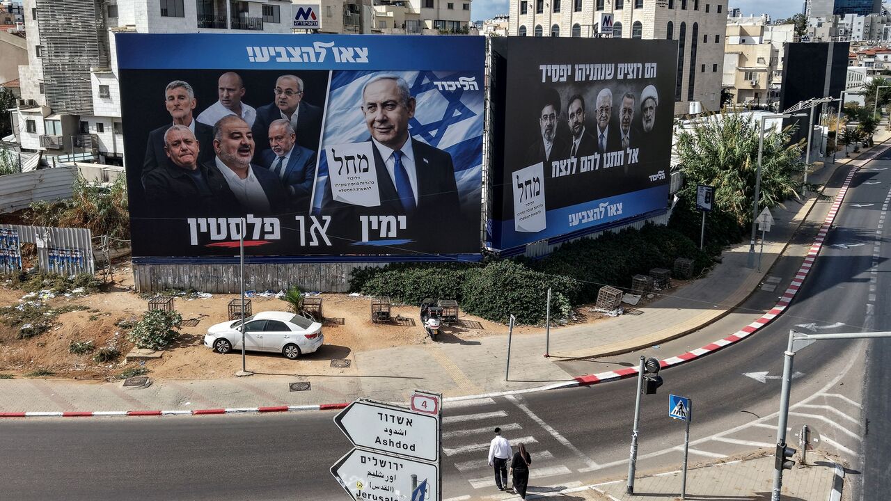 Pedestrians cross a street in front of a banner featuring Israeli Prime Minister Benjamin Netanyahu