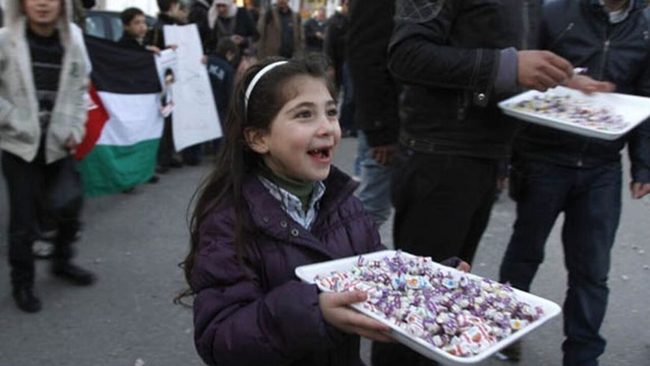 PALESTINIAN-PRISONER/DEAL A Palestinian girl hands out candies to passers-by in the West Bank city of Ramallah February 21, 2012 to celebrate the upcoming release of Islamic Jihad member Khader Adnan. Adnan, held without trial by Israel, agreed on Tuesday to end his 66-day hunger strike after Israeli authorities promised to release him in April in a deal that avoided judicial review of the detention policy. REUTERS/Mohamad Torokman (WEST BANK - Tags: POLITICS SOCIETY)